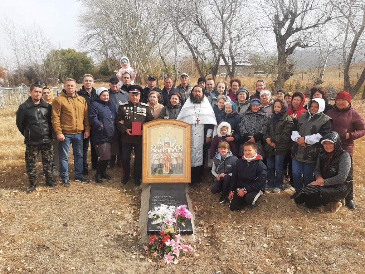 Групповое фото у памятника расстрелянным в станице Подгорненской: священник в белом облачении, казак в форме с наградами, около тридцати пяти человек, перед ними икона на подставке и плита с надписью